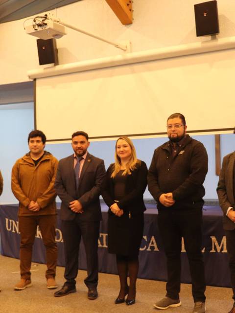 Un grupo de seis personas posan en una sala de conferencias en la Universidad Católica.