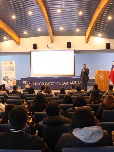 Un seminario en la Universidad Católica del Maule con un ponente frente a una audiencia.