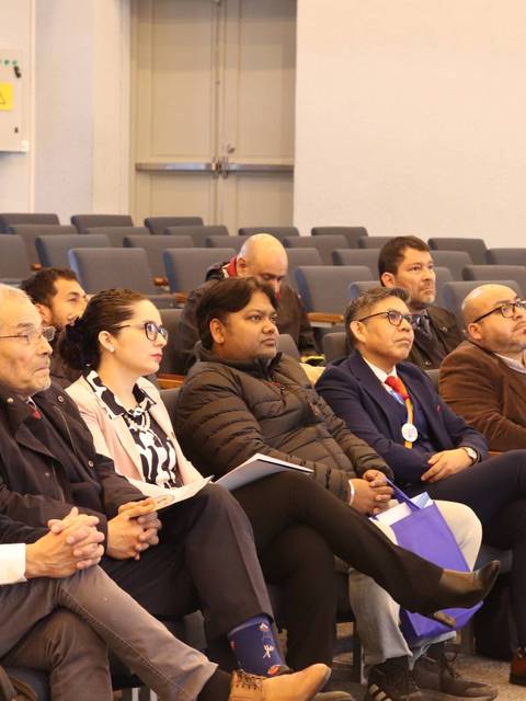 Un grupo de personas escucha atentamente en una sala de conferencias.