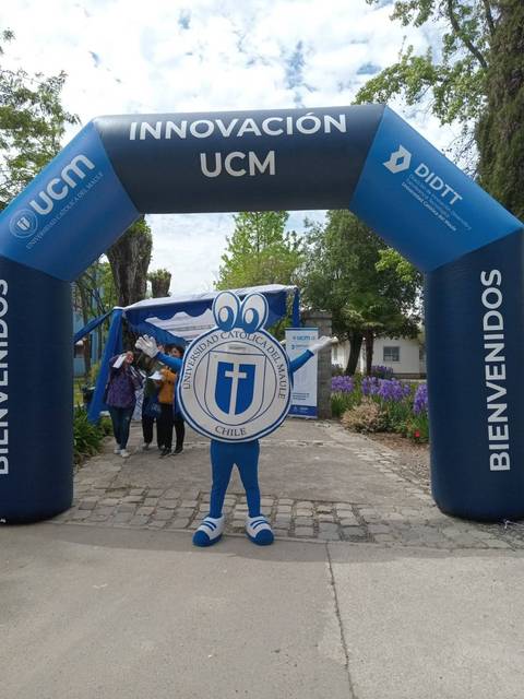 Un personaje disfrazado se encuentra bajo un arco inflable que dice 'INNOVACIÓN UCM'.
