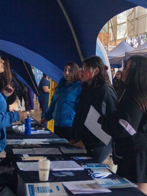 Una feria donde personas interactúan en un stand de información.