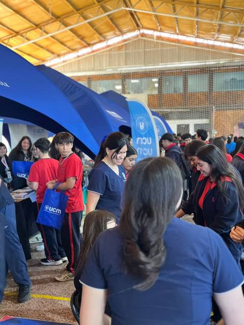 Un grupo de personas interactuando en un evento educativo con stands y actividades.