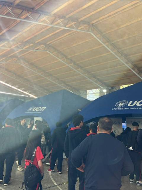 Una multitud de personas se aglomera bajo unas carpas de la Universidad Católica del Maule en un evento.