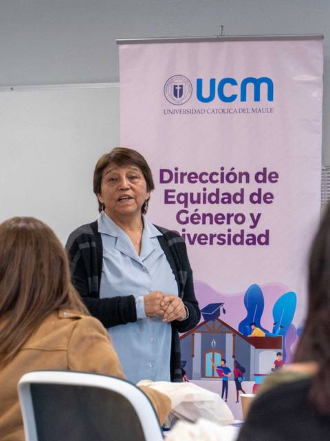 Una mujer dando una charla sobre equidad de género en un aula.