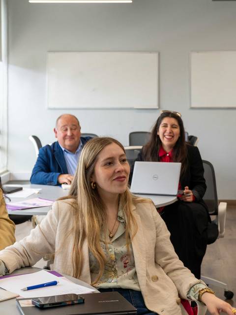 Un grupo de personas sonríen y participan en una actividad dentro de un aula moderna.