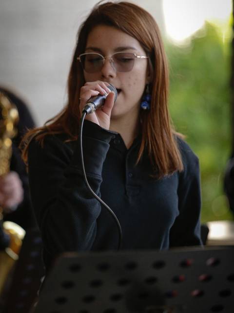 Una joven canta en un ambiente musical al aire libre.
