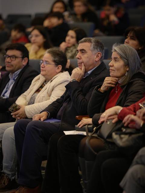 Un grupo de personas sentadas en un auditorio escuchando atentamente un evento.