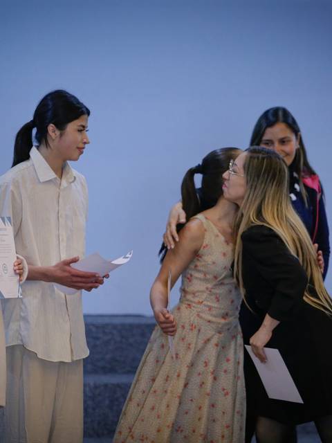 Un grupo de personas interactúa en un escenario mientras sostienen papeles en las manos.