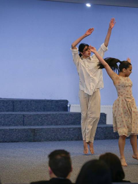 Dos bailarinas se presentan en un escenario con una coreografía en un salón con ambiente religioso.