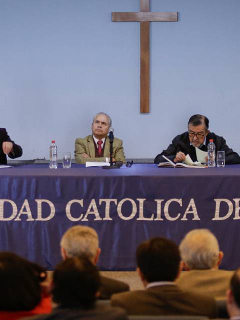 Un panel de discusión en la Universidad Católica del Maule con varios oradores y una audiencia visible.