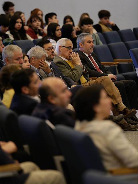 Un grupo de personas sentadas en un auditorio prestando atención a un evento.