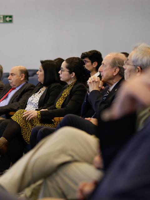 Un grupo de personas sentadas en un auditorio prestando atención a una presentación.