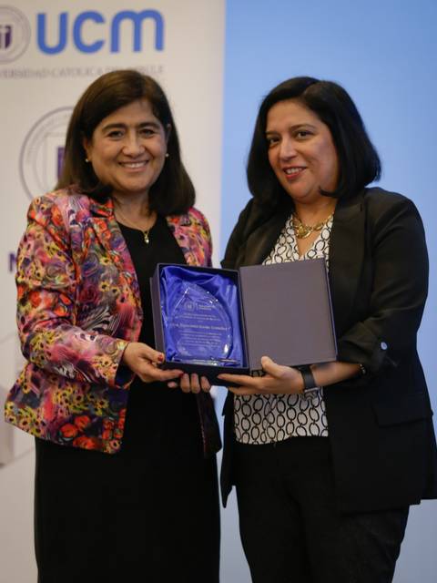 Dos mujeres sosteniendo un premio en un evento formal.