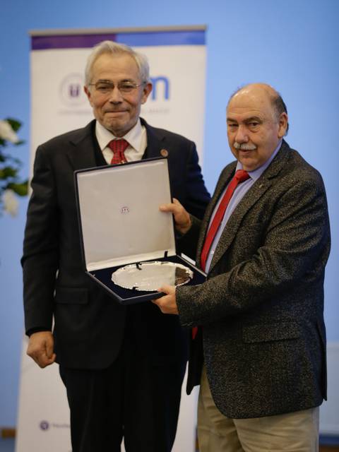 Dos hombres se están mostrando un reconocimiento en un evento formal.