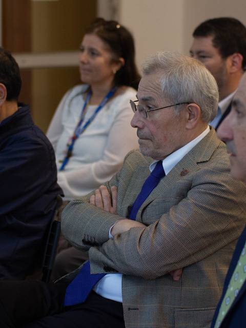 Un grupo de personas sentadas en una reunión, prestando atención al ponente.