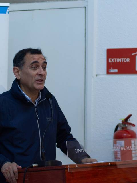 Un hombre habla frente a un público en un evento de la Universidad Católica del Maule en Curicó.