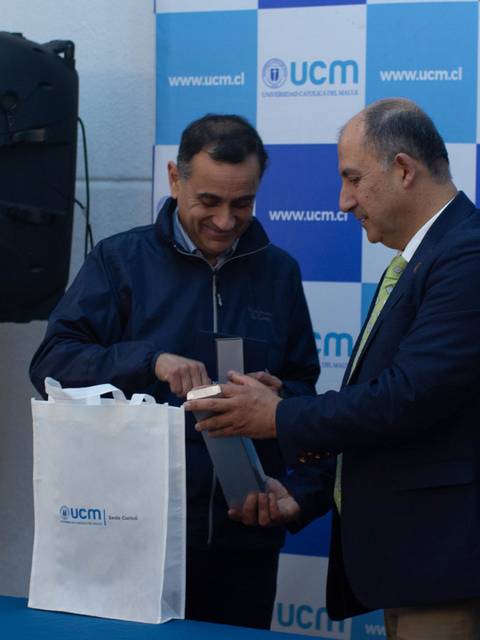 Una ceremonia de entrega de un reconocimiento en la UCM con varias personas presentes.