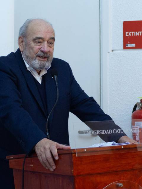 Un hombre de edad avanzada habla desde un atril en un evento en la universidad.