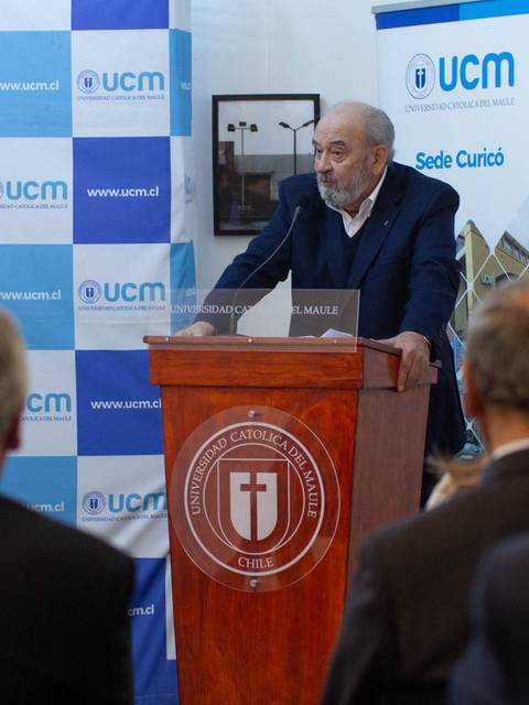 Una persona habla desde un podio en un evento formal frente a un público.