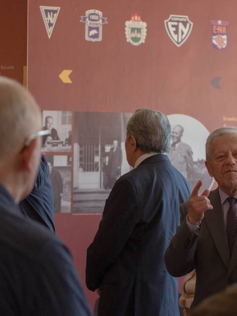 Un grupo de personas observa una exposición en un museo, mientras un hombre habla en el frente.