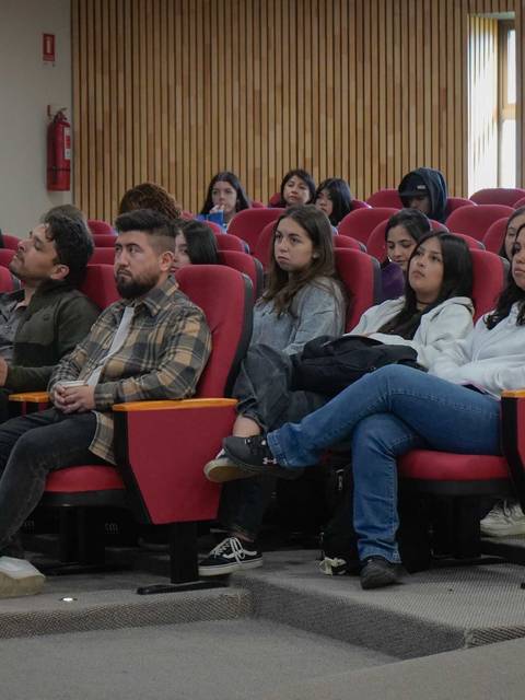 Un grupo de personas sentadas en un auditorio mirando hacia el frente.