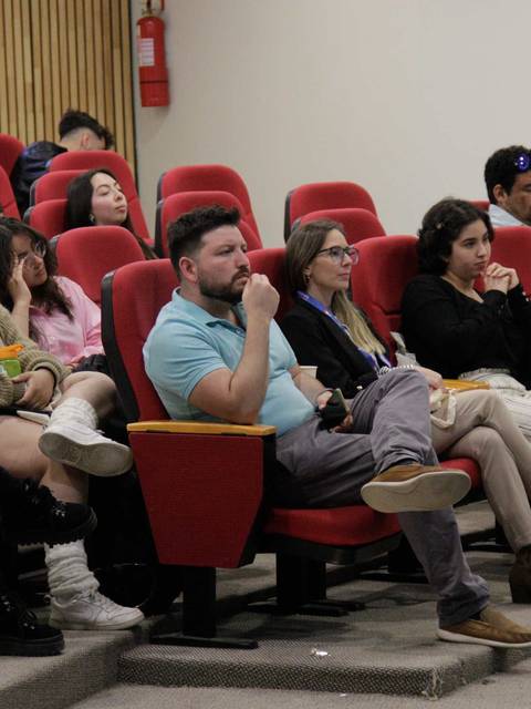 Un grupo de personas sentadas en un auditorio viendo una presentación.