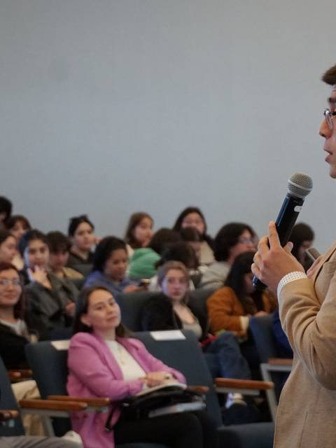 Un orador da una charla frente a una audiencia atenta en un evento académico.
