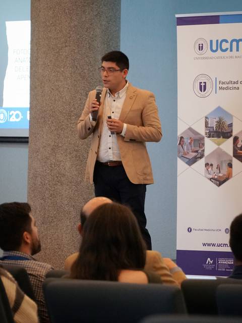 Un hombre en un escenario presenta un tema durante un evento académico.