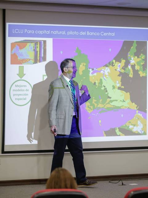 Un ponente presenta un mapa en una conferencia sobre el uso de la tierra y capital natural.