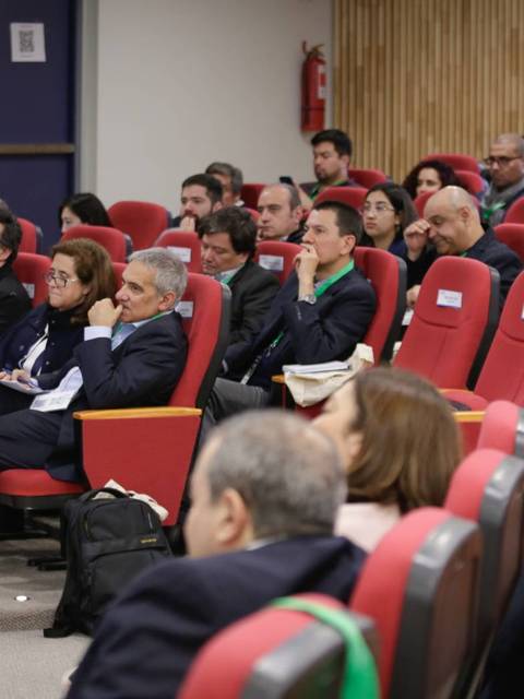 Un grupo de personas sentadas en una sala de conferencias atendiendo a una presentación.