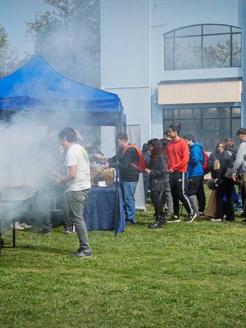 Un grupo de personas disfrutando de un evento al aire libre con parrillas y humo.
