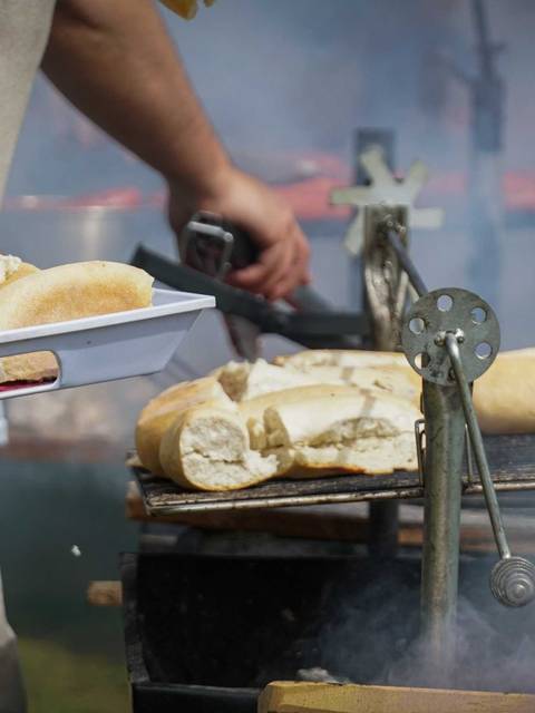 Un hombre está sirviendo pan mientras cocina en una parrilla con humo.