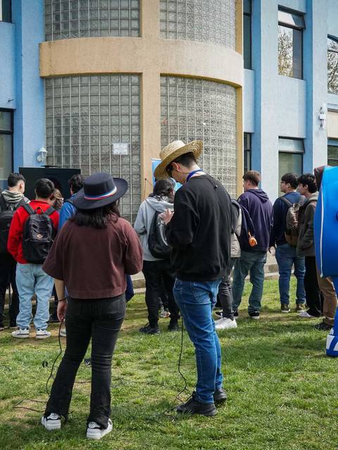 Un grupo de personas se reúne frente a un edificio de color azul en un día claro.