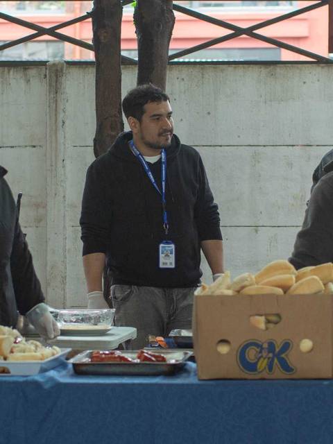 Un grupo de personas preparan y sirven alimentos en un espacio al aire libre.