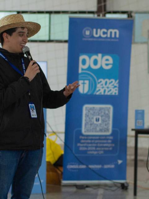Dos personas están conversando en un evento mientras sostienen micrófonos.