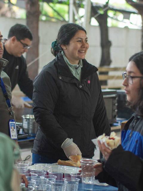 Un grupo de personas interactuando en un evento mientras se sirven bebidas y alimentos.