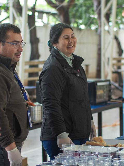 Un grupo de personas sonriendo y sirviendo alimentos en un evento.