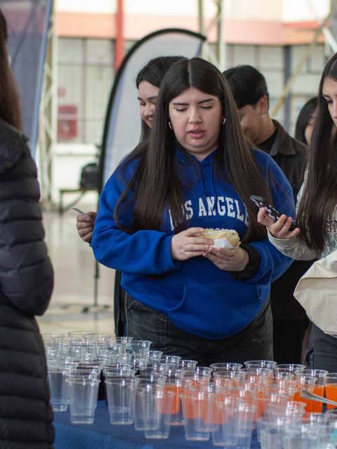 En la imagen se observa un grupo de jóvenes disfrutando de un evento mientras eligen entre varias bebidas y alimentos.