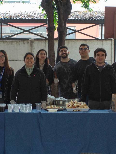 Un grupo de personas se reúne en un evento social con una mesa de comida y bebida.