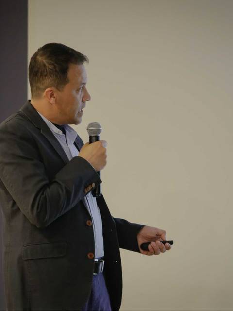 Un hombre está dando una presentación en una sala con un proyector.