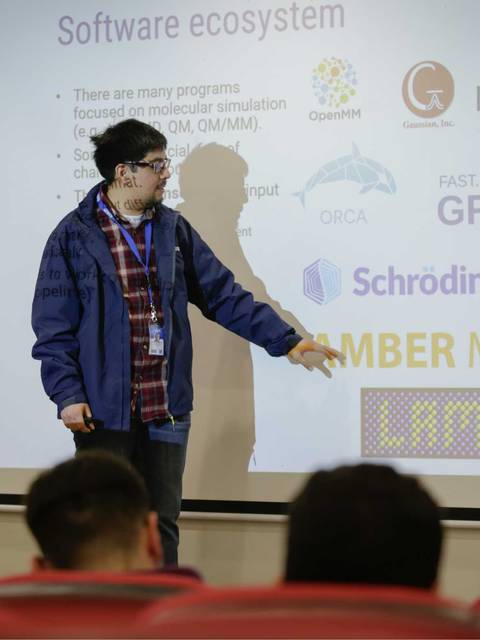 Un ponente presenta información sobre un ecosistema de software para simulaciones moleculares en una conferencia.