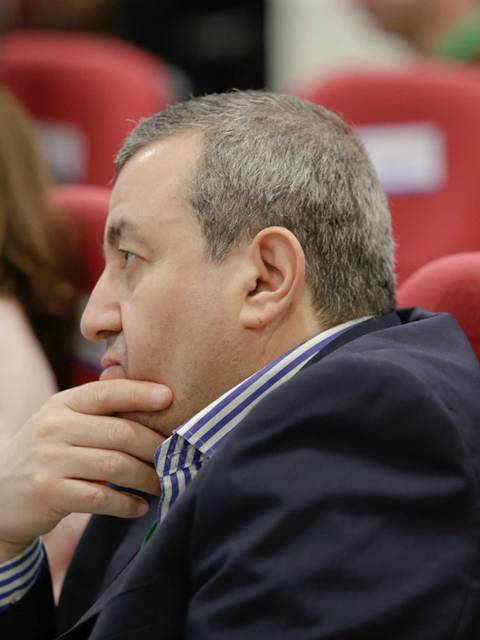 Un hombre pensativo está sentado en una sala con sillas rojas.