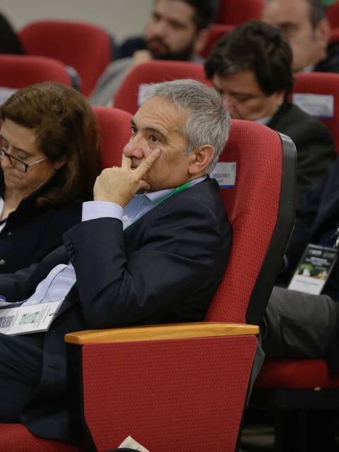 Un grupo de personas atentamente escuchando durante una conferencia, sentados en sillas rojas.