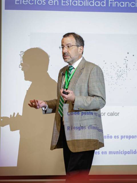Un hombre presenta un gráfico sobre los efectos en la estabilidad financiera en una conferencia.