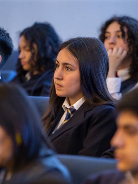 Un grupo de estudiantes escuchando atentamente en un evento.