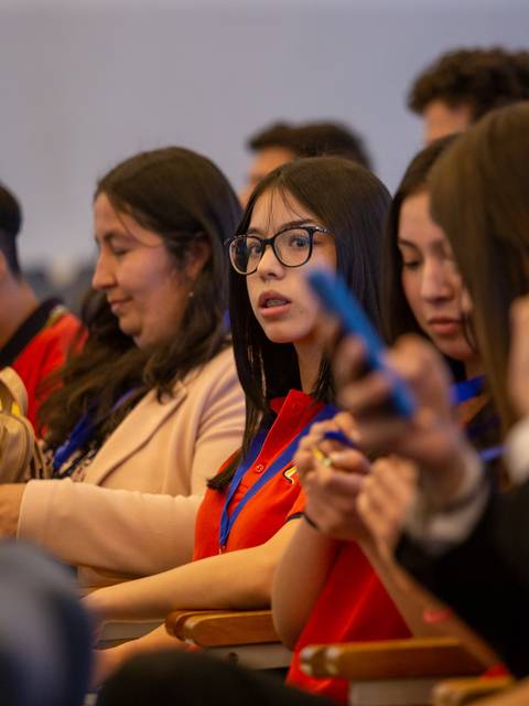 Un grupo de jóvenes y adultos escuchando atentamente en un evento.