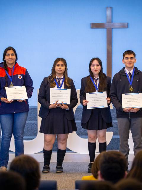 Un grupo de estudiantes recibe certificados de reconocimiento en un evento escolar.