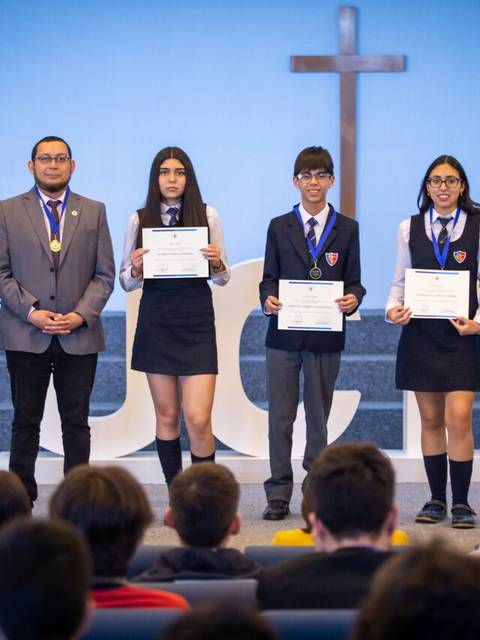 Un grupo de estudiantes junto a sus maestros en una ceremonia de premiación.