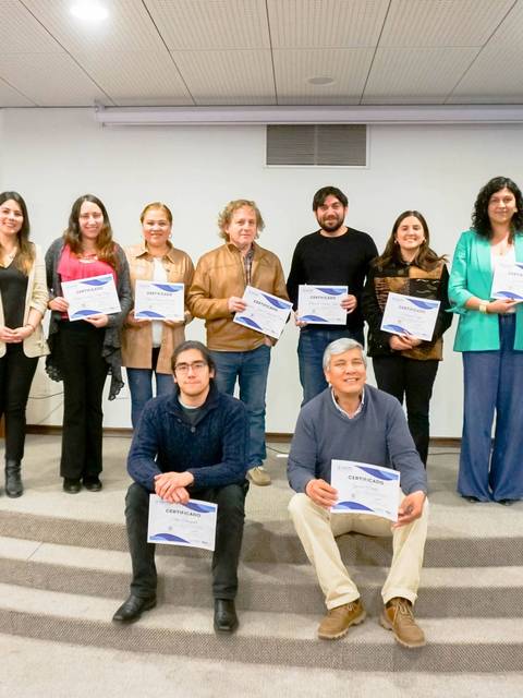Un grupo de personas sonrientes sostiene certificados en un evento institucional.