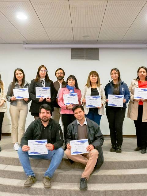 Un grupo de personas posando con certificados en un evento formal.